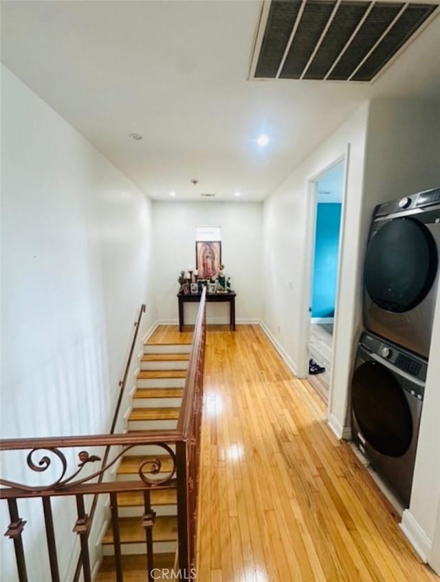 interior space with visible vents, laundry area, stacked washer and clothes dryer, light wood-style floors, and baseboards