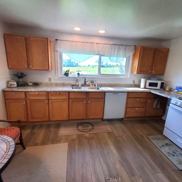 kitchen featuring light countertops, dark wood-style flooring, a sink, and white appliances