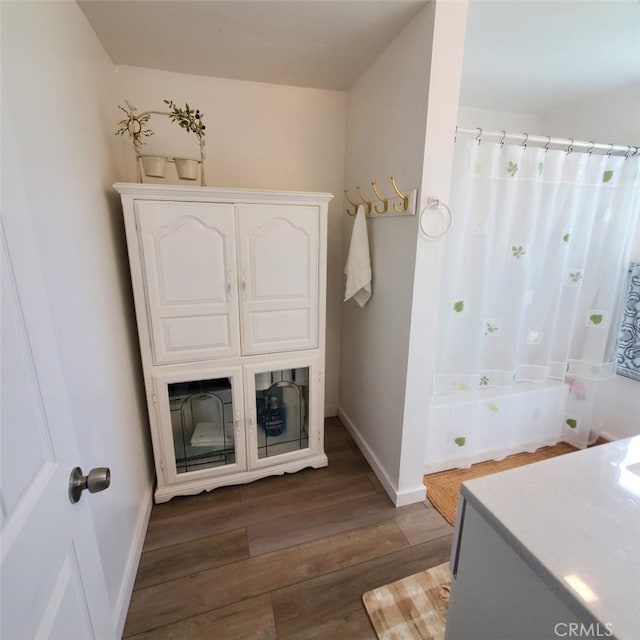 full bath featuring baseboards, a shower with curtain, and wood finished floors