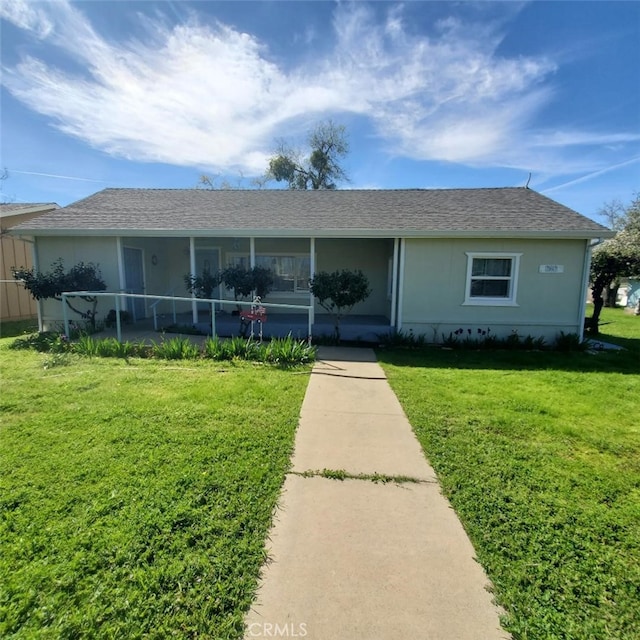 view of front of home with a shingled roof, covered porch, stucco siding, and a front lawn