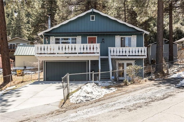rustic home with a balcony, concrete driveway, french doors, fence private yard, and an attached garage