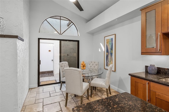 dining space featuring lofted ceiling, stone tile floors, baseboards, and a textured wall