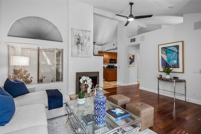 living room with baseboards, lofted ceiling, a ceiling fan, wood finished floors, and a brick fireplace