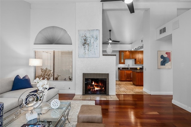 living room with a fireplace with flush hearth, light wood-style floors, and a ceiling fan