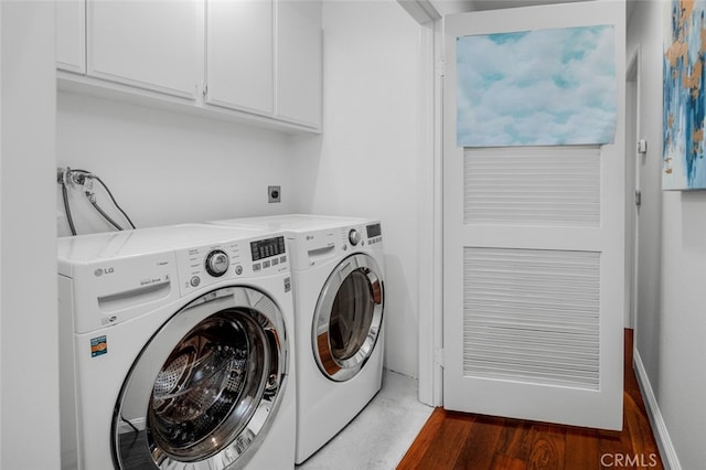 clothes washing area featuring wood finished floors, independent washer and dryer, and cabinet space