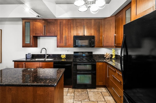 kitchen featuring dark stone countertops, a sink, black appliances, stone tile floors, and a chandelier