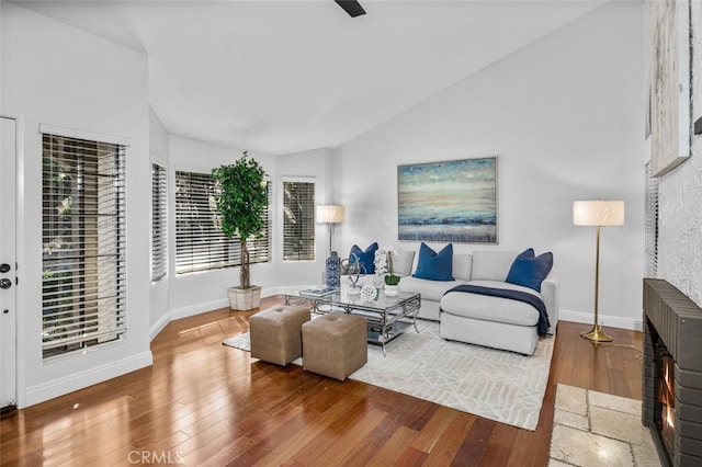 living room featuring hardwood / wood-style flooring, lofted ceiling, and baseboards