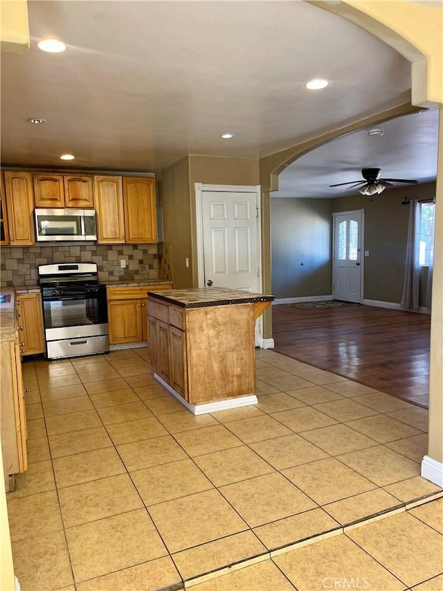 10715 3rd Ave, Hesperia, CA 92345 - kitchen featuring appliances with stainless steel finishes, arched walkways, open floor plan, tasteful backsplash, and a kitchen island