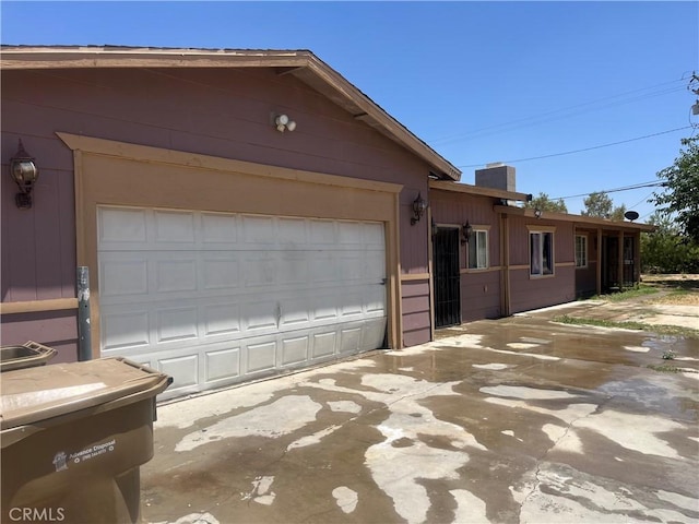 10715 3rd Ave, Hesperia, CA 92345 - view of home's exterior with concrete driveway, an attached garage, and a chimney