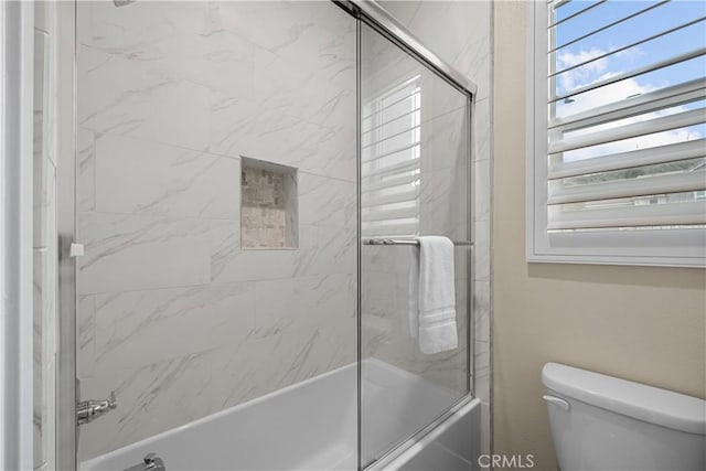 full bath featuring toilet and shower / bath combination with glass door