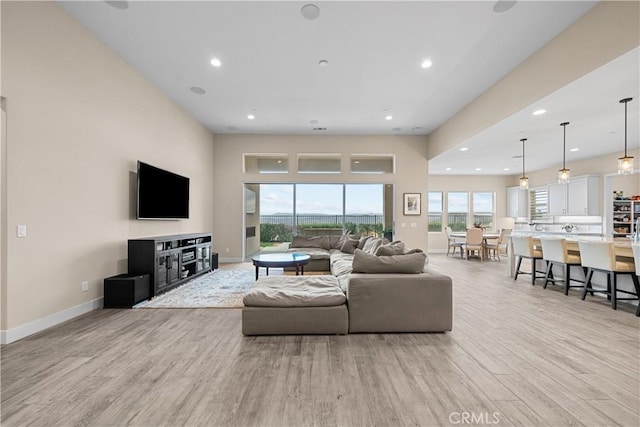 living area with recessed lighting, baseboards, and light wood-style floors