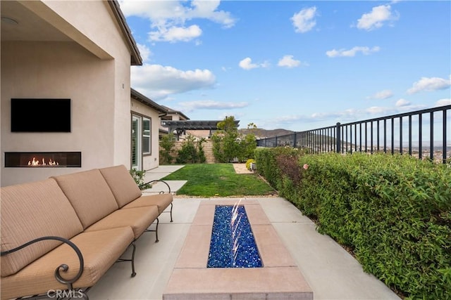 view of patio / terrace with a fenced backyard and an outdoor living space with a fireplace