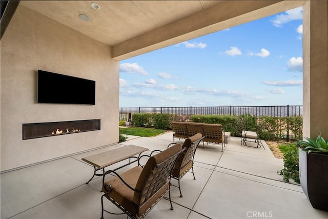 view of patio featuring a glass covered fireplace and fence