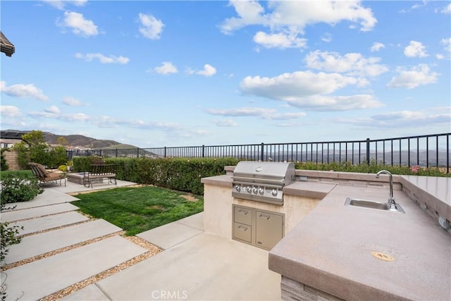view of patio / terrace featuring fence, a sink, exterior kitchen, and area for grilling