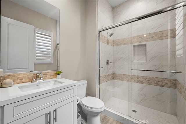 bathroom featuring vanity, toilet, decorative backsplash, and a stall shower