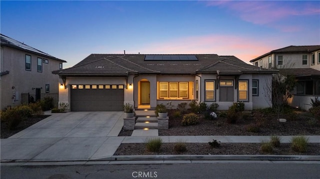 ranch-style house with solar panels, a tile roof, concrete driveway, an attached garage, and stucco siding