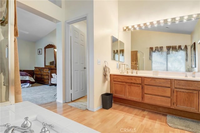 bathroom featuring a sink, ensuite bath, wood finished floors, and double vanity