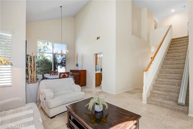 living area with high vaulted ceiling, visible vents, baseboards, stairway, and an inviting chandelier