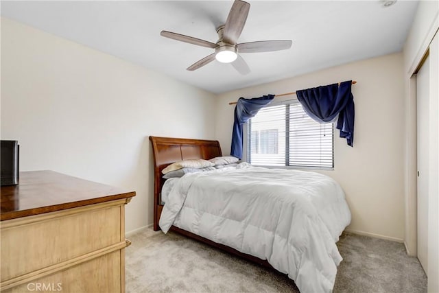 bedroom with light colored carpet, a closet, ceiling fan, and baseboards