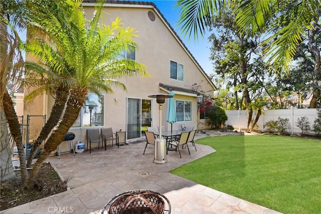 back of house with a fenced backyard, stucco siding, a patio area, and a lawn