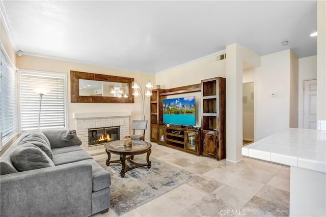 living area with a brick fireplace, light tile patterned flooring, crown molding, and visible vents