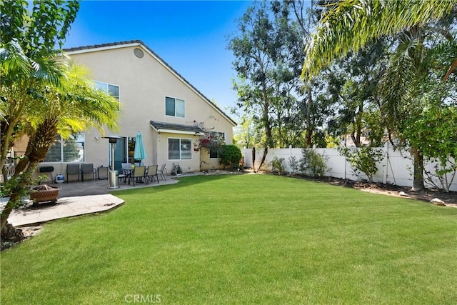 rear view of house featuring a patio, a fenced backyard, stucco siding, a fire pit, and a yard
