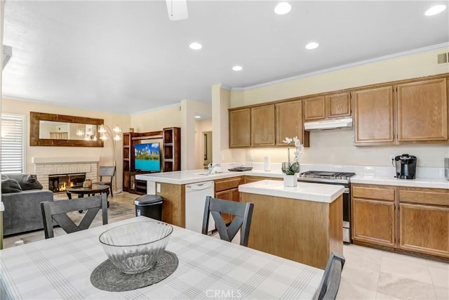 kitchen featuring dishwasher, a peninsula, under cabinet range hood, stainless steel gas range oven, and tile countertops
