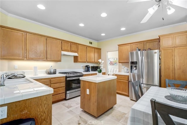 kitchen with ornamental molding, a ceiling fan, appliances with stainless steel finishes, under cabinet range hood, and a sink
