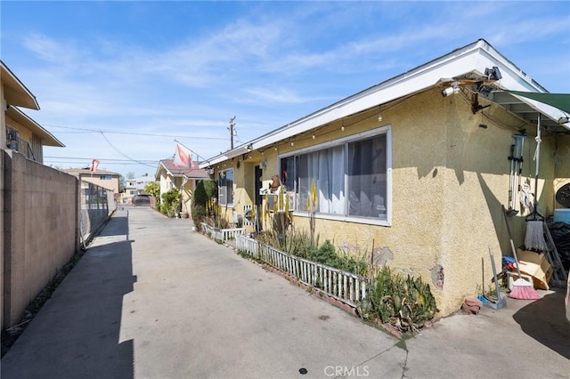 view of side of home with stucco siding and fence