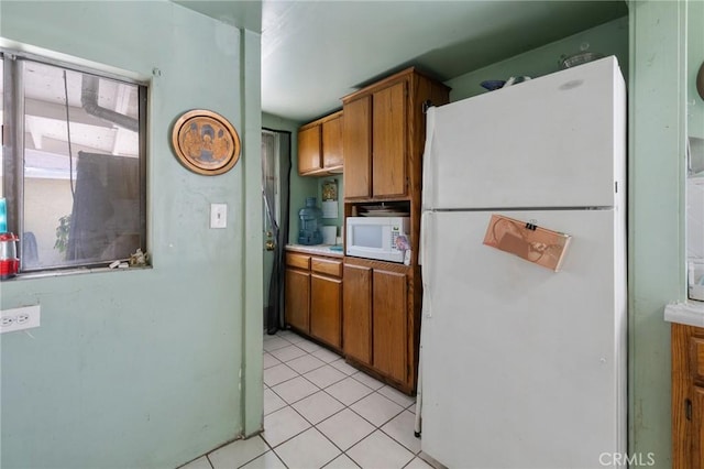 kitchen with white appliances, brown cabinets, light countertops, and light tile patterned floors