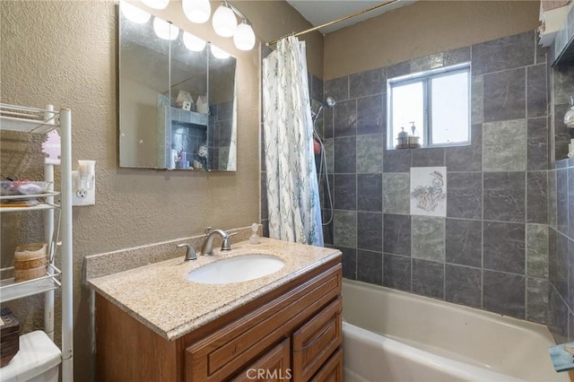 bathroom with shower / tub combo with curtain, vanity, and a textured wall