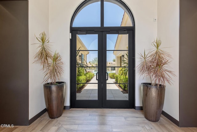 entryway with wood finished floors, baseboards, and french doors