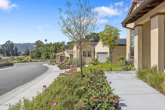 view of home's exterior featuring stucco siding, roof mounted solar panels, and a mountain view