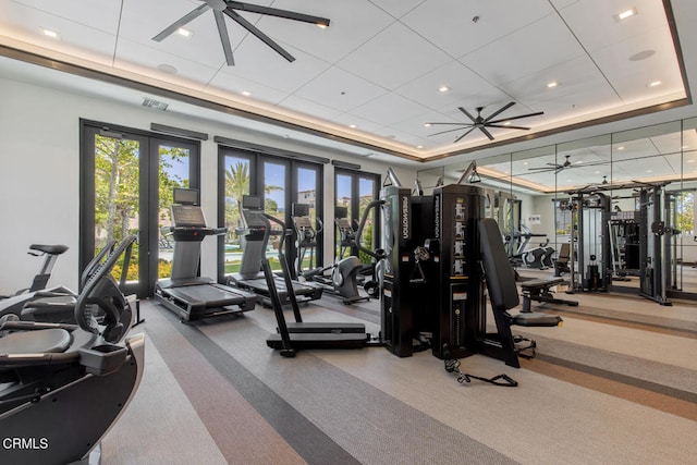 gym with french doors, a tray ceiling, visible vents, ceiling fan, and carpet floors