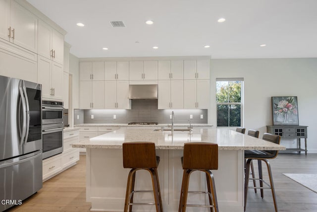 kitchen featuring decorative backsplash, appliances with stainless steel finishes, a sink, and white cabinets