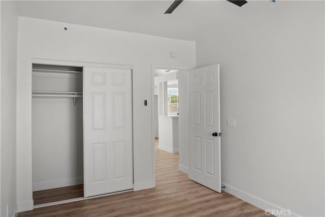 unfurnished bedroom featuring a closet, baseboards, wood finished floors, and a ceiling fan