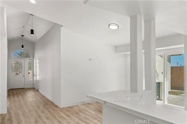 entrance foyer with baseboards, light wood-style floors, and lofted ceiling