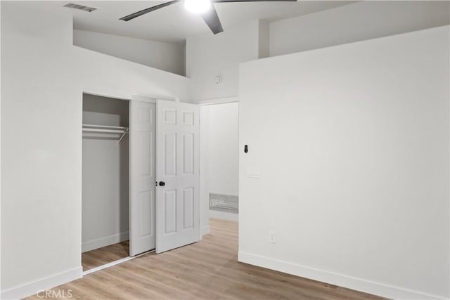 unfurnished bedroom with a closet, visible vents, baseboards, wood finished floors, and lofted ceiling