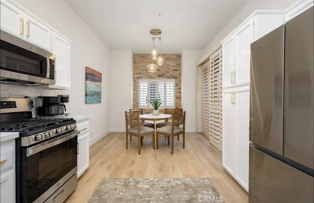 kitchen with white cabinetry, light countertops, light wood-style flooring, and appliances with stainless steel finishes