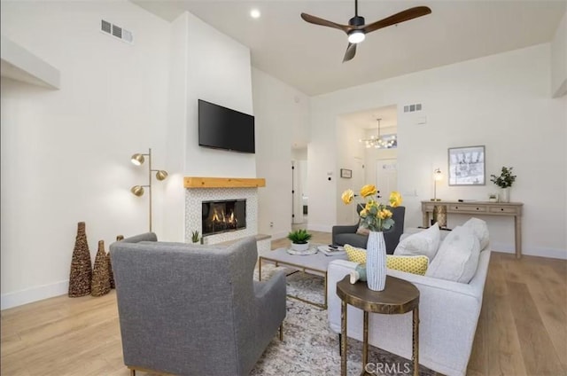 living room featuring ceiling fan with notable chandelier, light wood finished floors, and visible vents