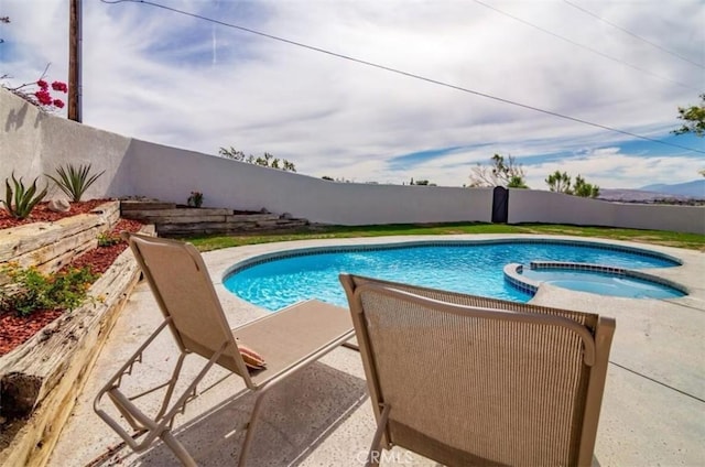 view of swimming pool with a fenced backyard and a pool with connected hot tub