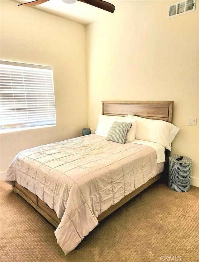 carpeted bedroom with baseboards, visible vents, and a ceiling fan