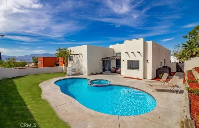 rear view of house with a fenced backyard, a pool with connected hot tub, stucco siding, and a patio area