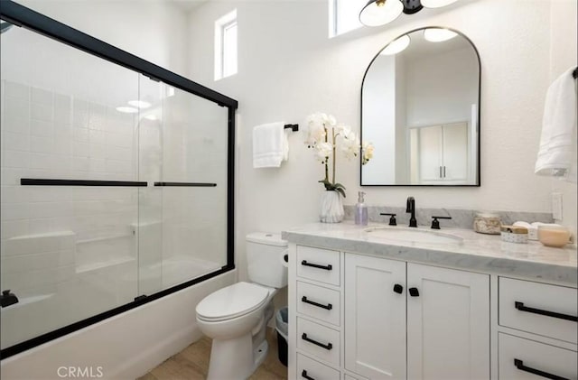 bathroom featuring toilet, vanity, and shower / bath combination with glass door