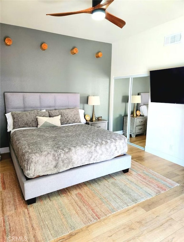 bedroom featuring visible vents, a closet, wood finished floors, and a ceiling fan