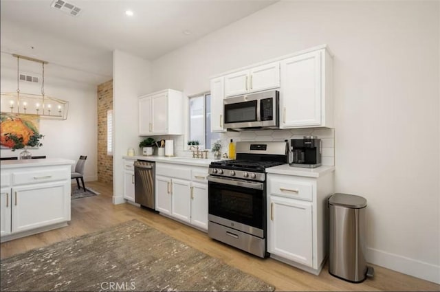 kitchen featuring decorative backsplash, white cabinetry, visible vents, and appliances with stainless steel finishes
