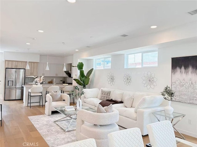 living room with light wood finished floors, visible vents, and recessed lighting