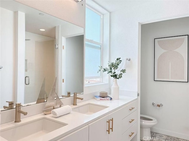 bathroom featuring a stall shower, double vanity, toilet, and a sink