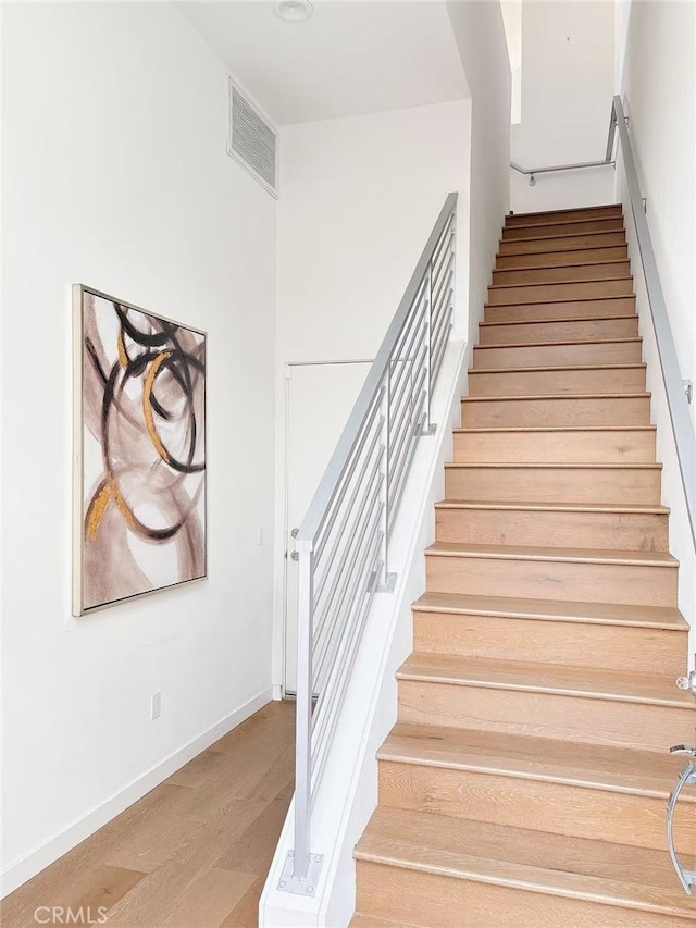 stairs with baseboards, visible vents, and wood finished floors