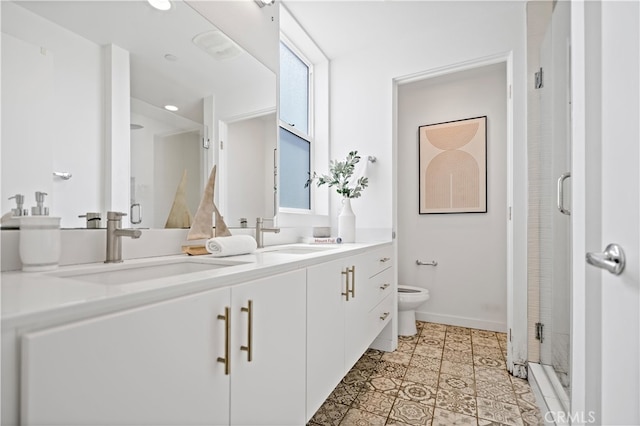 bathroom with a stall shower, double vanity, toilet, and a sink